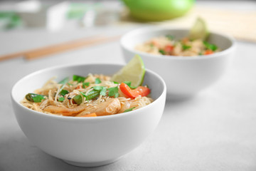 White plate with delicious rice noodle and vegetables on light table