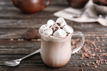 Glass cup of cocoa with marshmallows on wooden table