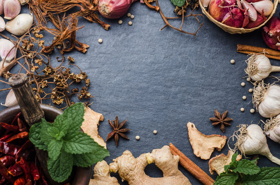 Various dried herbs with papermint on black stone background