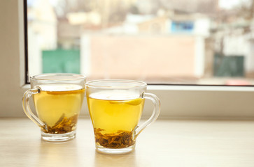 Cups of hot tea on window sill