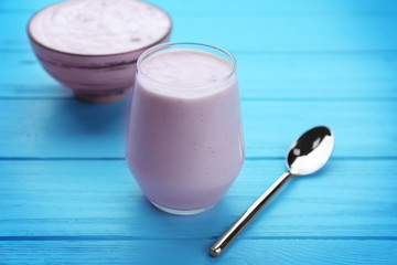 Glass with yogurt on wooden background
