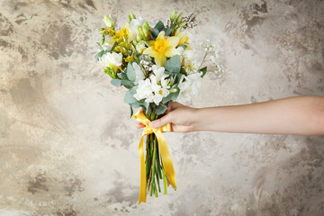 Woman holding bouquet with freesia flowers on textured background