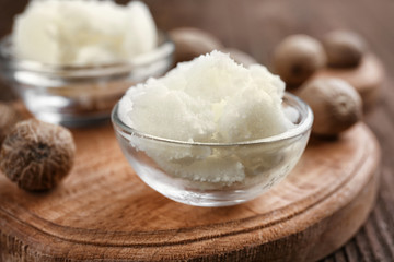 Shea butter in bowls on wooden background, close up