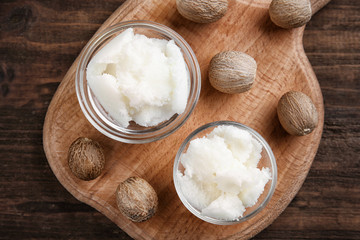 Shea butter in bowls on wooden background, top view