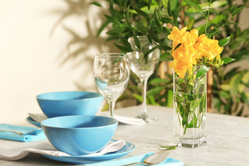 Beautiful festive table setting and vase of flowers in light room
