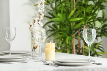 Beautiful festive table setting and vase of flowers in light room