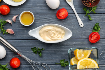 Obraz na płótnie Canvas Mayonnaise in gravy boat with ingredients on wooden background, top view