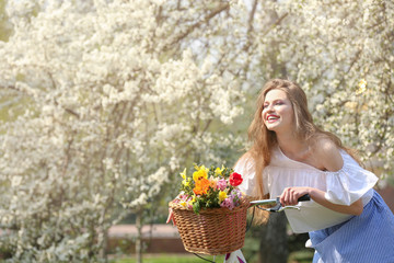 Pretty young girl standing near bicycle in park