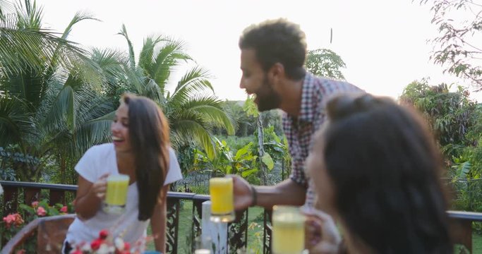 People Group Holding Juice Glasses Talking Sitting At Table Outdoors On Terrace Young Friends Happy Smiling Communication Slow Motion 60