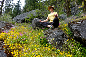 Naklejka na ściany i meble Young woman meditating in nature. Wildflowers in alpine meadows. Cascade Mountains. Seattle. Leavenworth. WA. The United States.