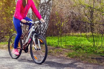 Close-up of a young woman riding a bike on a path in the forest on a summer day