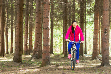 Obraz premium A woman is riding a bicycle in a pine forest