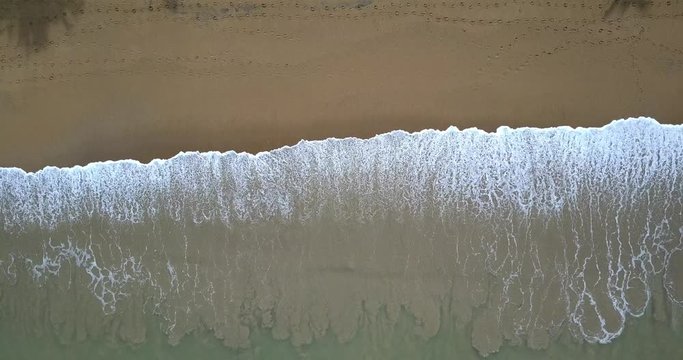 Aerial footage of a tropical beach with waves from top view. Summer vacation holiday.