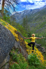 Woman in yoga pose in mountains among yellow wildflowers in spring. Central Cascade Mountains.  Portland. Vancouver. Oregon.  The United States.