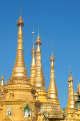 The tops of the golden stupas of the Shwedagon pagoda against the blue sky. Yangon, Myanmar