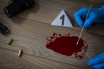 Forensic experts takes a sample of blood from the crime scene