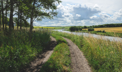 Fototapeta na wymiar Sunny summer landscape with ground road and river
