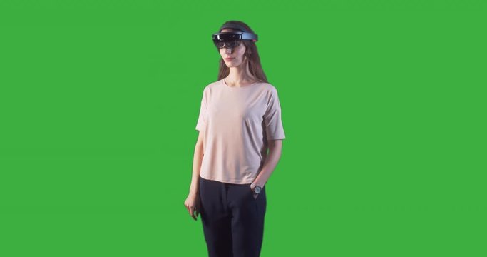 Young adult Caucasian female using holographic augmented reality glasses. Green screen chroma key. Left side key light. 4K UHD RAW edited footage