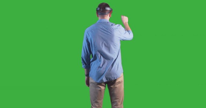 Young adult Caucasian male using holographic augmented reality glasses. Green screen chroma key. Right side key light. 4K UHD RAW edited footage