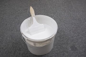 White plastic bucket and brush on the floor.