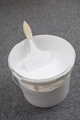 White plastic bucket and brush on the floor.