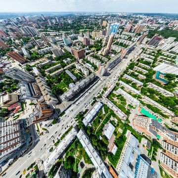 Aerial city view with crossroads and roads, houses, buildings, parks and parking lots, bridges. Helicopter drone shot. Wide Panoramic image.