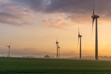 wind wheels at sunrise and fog with dark clouds