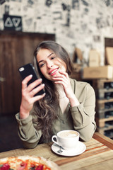 Pretty Girl Using Cell Phone Smiles.In caffe.With coffe and pizza.