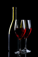 Wine glass and bottle with red wine isolated on black