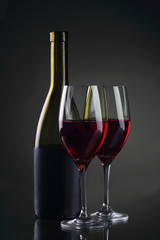 Wine glass and bottle with red wine on gray