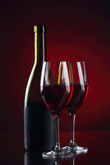 Wine glass and bottle with red wine on red