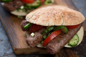 Close-up of pita bread filled with barbecued cevapcici or skinless beef sausages, shallow depth of field, horizontal shot