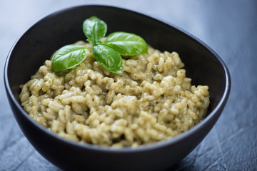 Closeup of a black bowl with spinach risotto, horizontal shot, selective focus