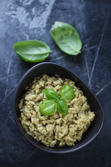Bowl with spinach risotto on a dark grey stone background, high angle view