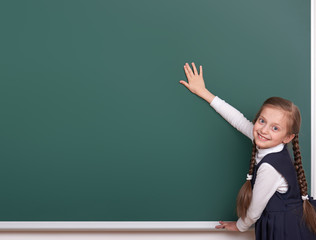 elementary school girl put hands on chalkboard background and show blank space, dressed in classic black suit, group pupil, education concept