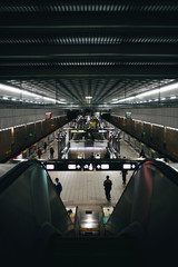 Going down the escalator of a subway station Taipei with silhouettes of people