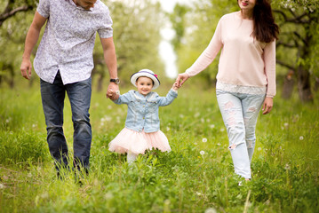 Family mom, dad and daughter are walking in the spring in a flowery garden, happy, laughing