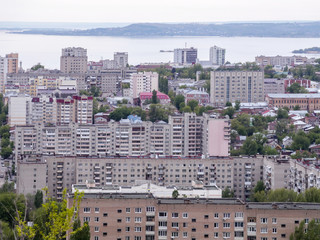 View of the city of Saratov from the mountain. The urban landscape, infrastructure, tenement houses, public buildings and streets, the Volga river on the horizon. Russian province.