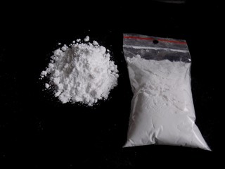 Cocaine drug powder bag and pile on black background