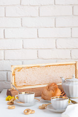 Honey with honeycomb and tea with teapot and flowers on the background, place for text