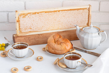 Black tea with buns and honey in honeycomb, whate background