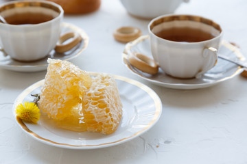 Honeycomb on a plate with tea cups on background
