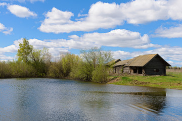 Obraz premium Old wooden house on the shore of the reservoir in the spring