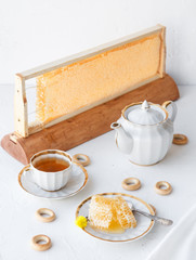 Cups of tea with honeycomb and bagels on a white background