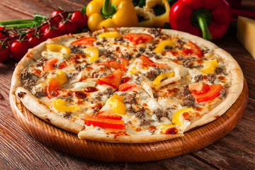 Delicious hot pizza sliced and served on wooden table with ingredients. Italian restaurant menu photo.