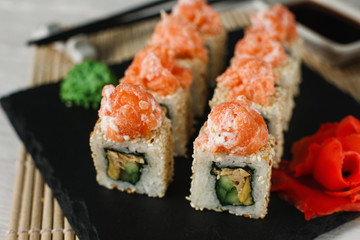 Appetizing and fresh set of sushi uramaki rolls served on black slate, close up. Traditional Asian food, Japanese healthy seafood.