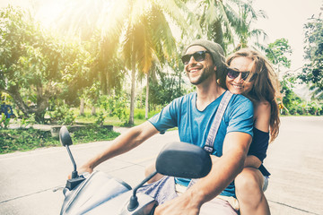 Obraz premium Young beautiful couple rides the jungle on a scooter, travel, freedom, happiness, vacation, honeymoon concept
