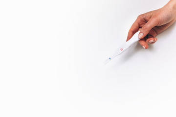 Pregnancy positive test in female hand, flat lay white background with free space. In vitro fertilization success, pregnant woman, happy maternity concept.