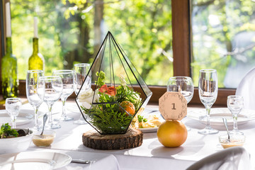 Rustic decorations in banquet hall. Table decoration minimalist florarium, succulents, oranges, greenery