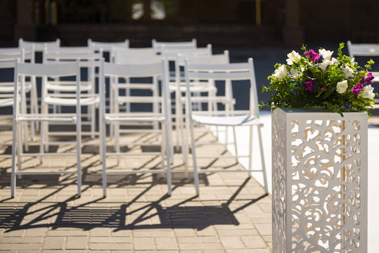 White lace wedding arch and chairs for guests. Vases with purple flowers. The wedding ceremony area at the wedding
